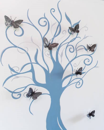 disegno su muro di albero azzurro con farfalle sui rami in rilievo
